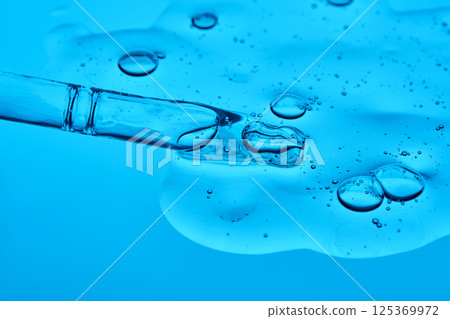 Hydrolyzed sponge serum with a pipette on a blue background. Hydrolyzed sponge serum with a pipette on a blue background. 125369972