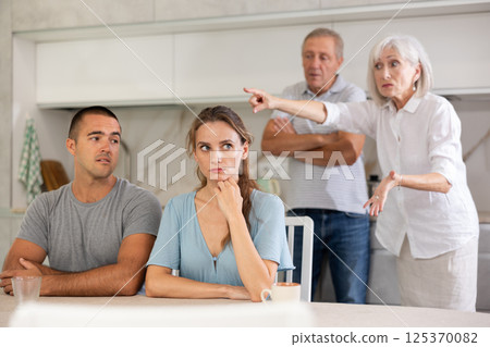 Elderly parents make claims to young couple in kitchen 125370082