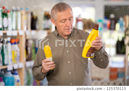 Elderly man buys a cleaning product for washing parquet and laminate floors in supermarket Elderly man buys a cleaning product for washing parquet and laminate floors in supermarket 125370115