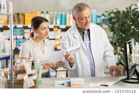 Male pharmacist helps female customer find prescription medication Male pharmacist helps female customer find prescription medication 125370118