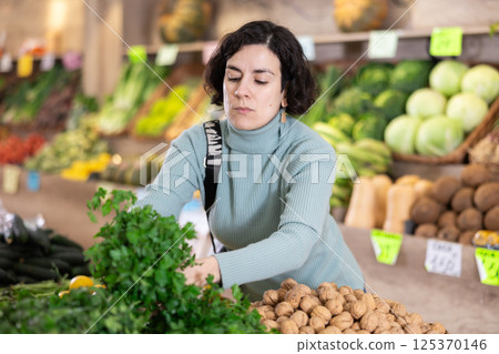 Adult woman chooses parsley in vegetable shop 125370146