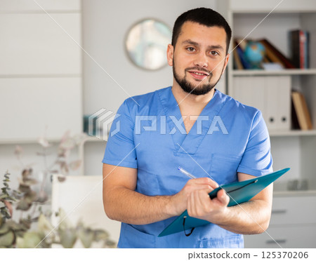 Portrait of positive male doctor with folder Portrait of positive male doctor with folder 125370206