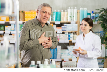 Mature man pharmacy client suffers from heartache. Girl pharmacist offer help 125370208