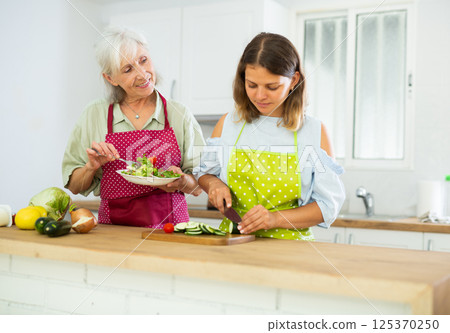 Elderly woman and her daughter preparing salad Elderly woman and her daughter preparing salad 125370250