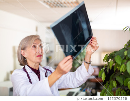 Female doctor examining x-ray closely in clinic closeup Female doctor examining x-ray closely in clinic closeup 125370256