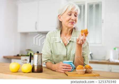 Relaxed elderly woman drinking coffee with muffin 125370340