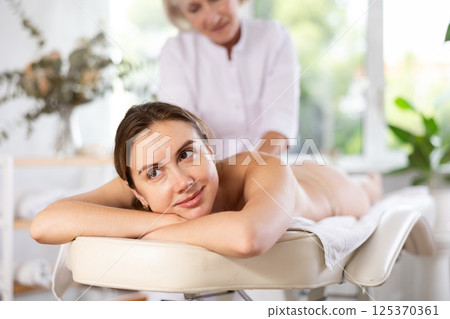 Young woman relaxing in spa center during professional back massage 125370361