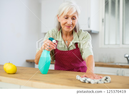Mature woman cleaning kitchen table at home 125370419