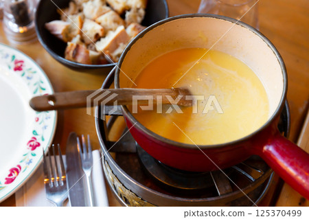 French variation of fondue, Fondue Savoyarde, preparing on table 125370499