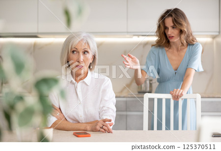 Adult woman quarreling with elderly woman in kitchen 125370511