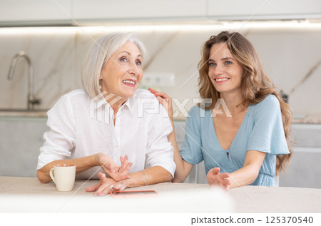 Adult woman and elderly woman drinking tea in kitchen 125370540