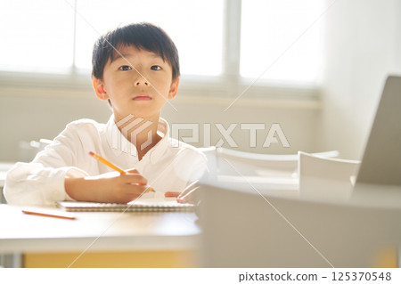 Elementary school boy studying in a bright classroom 125370548