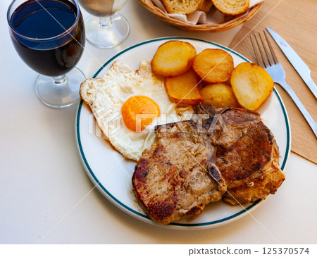 Plate with pork chop with potatoes and scrambled eggs Plate with pork chop with potatoes and scrambled eggs 125370574