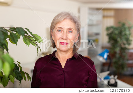 Positive good-looking aged female entrepreneur in office interior 125370580