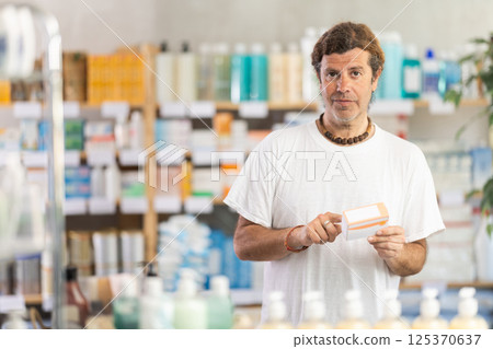Adult man chooses pills at pharmacy Adult man chooses pills at pharmacy 125370637