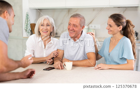 Family of four sits at table and talking Family of four sits at table and talking 125370678
