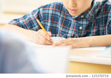 Elementary school boy writing with all his heart | Close-up of hands Elementary school boy writing with all his heart | Close-up of hands 125370719