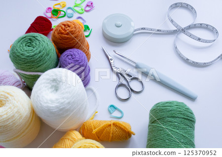 Colorful yarn balls and crochet tools on white surface 125370952