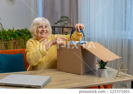Happy senior woman shopper unpack headphones cardboard box delivery parcel online shopping purchase Happy senior woman shopper unpack headphones cardboard box delivery parcel online shopping purchase 125371001