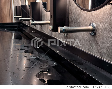 Modern bathroom sink with water spill and sleek metal fixtures Modern bathroom sink with water spill and sleek metal fixtures 125371002