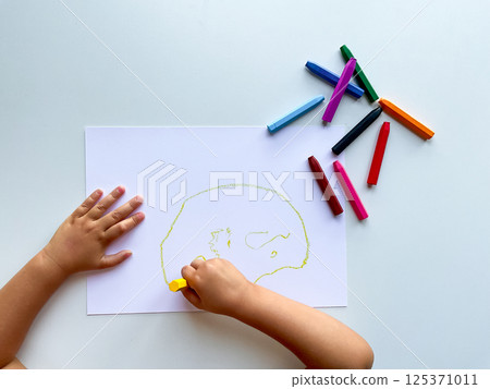 Child drawing with colorful crayons on white paper Child drawing with colorful crayons on white paper 125371011