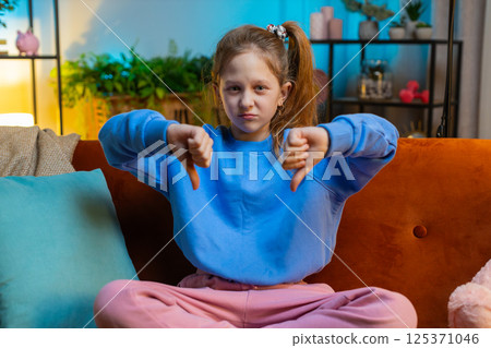 Upset teen girl showing thumbs down, dislike bad work, disapproval, dissatisfied feedback at home 125371046