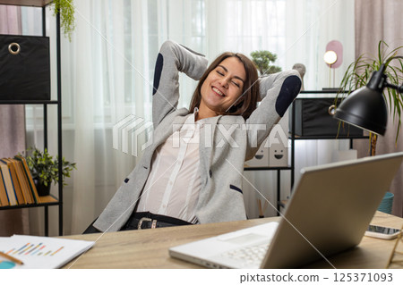 Businesswoman freelancer taking break leaning on chair after working celebrating success victory win 125371093
