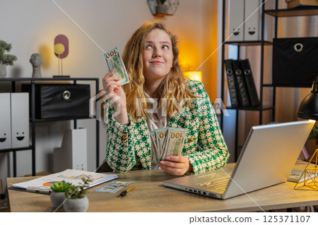 Business woman counting money cash and using laptop calculates dividends profits finances at office 125371107
