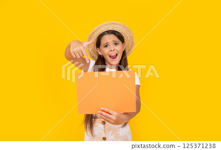 shocked teen kid with copy space on orange paper on yellow background. point finger 125371238