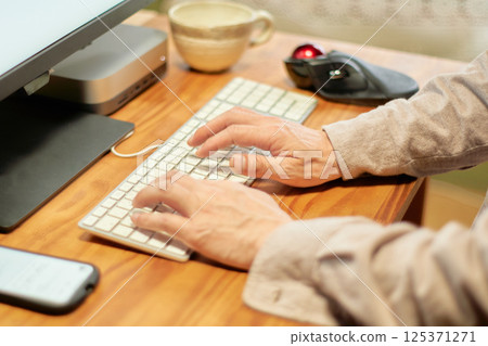 The hands of a man working on a computer while working from home The hands of a man working on a computer while working from home 125371271