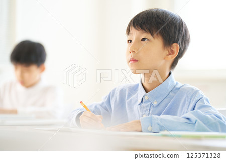 Male elementary school student studying in the classroom | Looking ahead with a serious expression 125371328