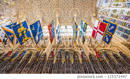 Visitors admire the intricate features of Henry VII Chapel in Westminster Abbey, London. Colorful flags adorn the high ceiling, showcasing its rich history and stunning architecture. Visitors admire the intricate features of Henry VII Chapel in Westminster Abbey, London. Colorful flags adorn the high ceiling, showcasing its rich history and stunning architecture. 125371447