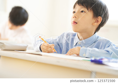 Male elementary school student studying in the classroom | Looking straight ahead Male elementary school student studying in the classroom | Looking straight ahead 125371500