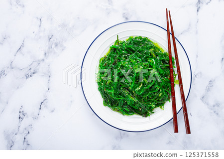 Chuka salad, made from fresh seaweed, with sesame dressing, served on a white plate, with chopsticks, no people, 125371558