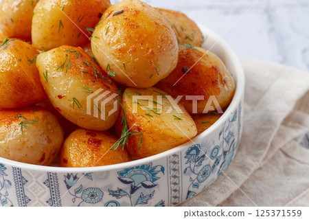 Baked new potatoes, with butter and dill, on a white plate, at home, no people, 125371559