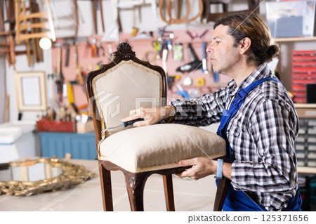 Male carpenter working on making vintage chair in workshop 125371656