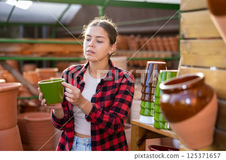 Portrait of woman choosing pots for flowers in gardening market 125371657