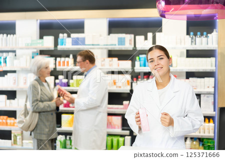 In pharmacy, female specialist holds and shows new effective remedy for moisturizing delicate skin In pharmacy, female specialist holds and shows new effective remedy for moisturizing delicate skin 125371666