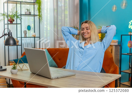 Business woman freelancer taking break leaning on chair after laptop working celebrating success 125372080