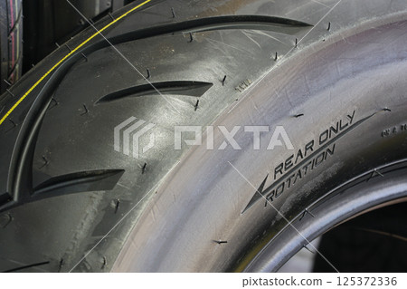 Close-up of the side of a new road motorcycle rear tire with the direction of rotation indicated 125372336