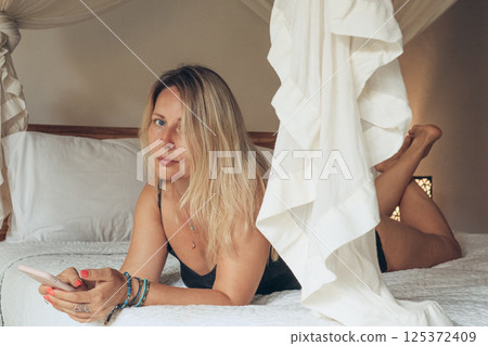 woman using smartphone in bedroom 125372409