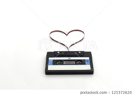 Retro audio stereo mono blue cassete with magnetic tape in shape of heart. Top view at the cassete Retro audio stereo mono blue cassete with magnetic tape in shape of heart. Top view at the cassete 125372620