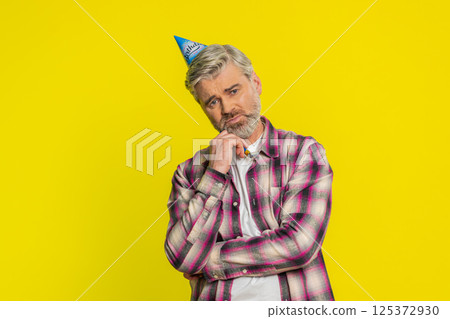 Mature man lonely birthday party cone hat, blower bored mood solitude celebration upset tired bored 125372930