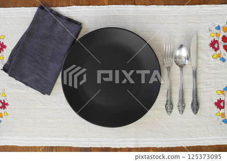 Empty black slate plate on dark stone table. Food background for menu, recipe. Table setting. 125373095