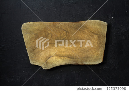 Empty wooden cutting board flat lay on black stone grunge background. Top view 125373098