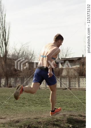 professional runner doing outdoor sports outside the city, sprinting, view from the back 125373232