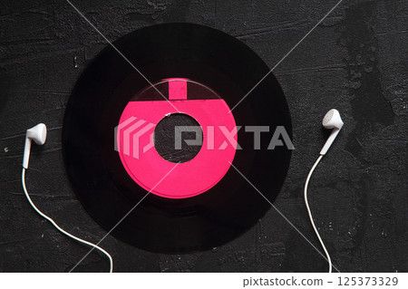 White headphones with wire and vinyl discs on an black background. Retro technique for playing music. 125373329