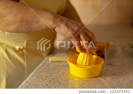 Close-up of a mature woman's hand squeezing juice from an orange 125373341