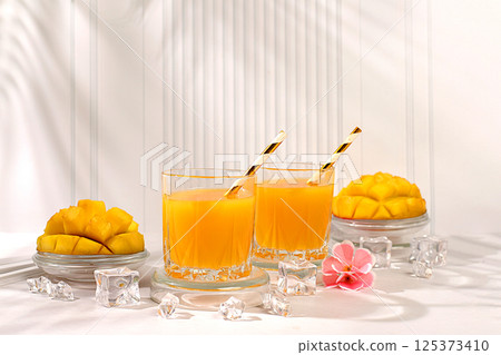 Modern still life with tropical fruits.Homemade cocktail, juice or lemonade with mango slices and ice on sunny kitchen table.Summer party concept and Detox diet, Restaurant menu Modern still life with tropical fruits.Homemade cocktail, juice or lemonade with mango slices and ice on sunny kitchen table.Summer party concept and Detox diet, Restaurant menu 125373410