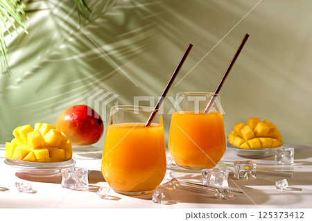 Homemade cocktail, juice or lemonade with mango slices and ice on sunny kitchen table.Summer party concept and Detox diet,Modern still life with tropical fruits.Restaurant menu Homemade cocktail, juice or lemonade with mango slices and ice on sunny kitchen table.Summer party concept and Detox diet,Modern still life with tropical fruits.Restaurant menu 125373412